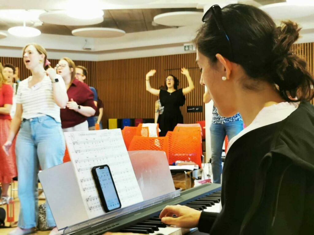 Paola Vera, coach vocale, accompagne au clavier un groupe de chanteurs en répétition